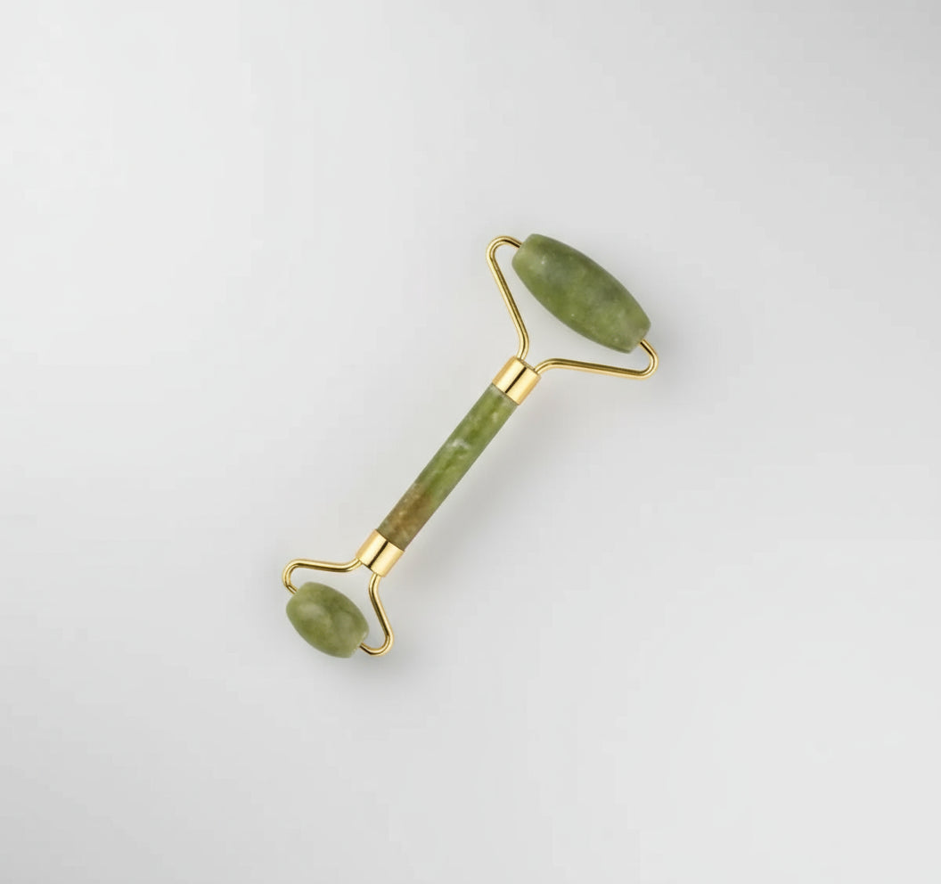 Jade facial roller with gold accents on a white background