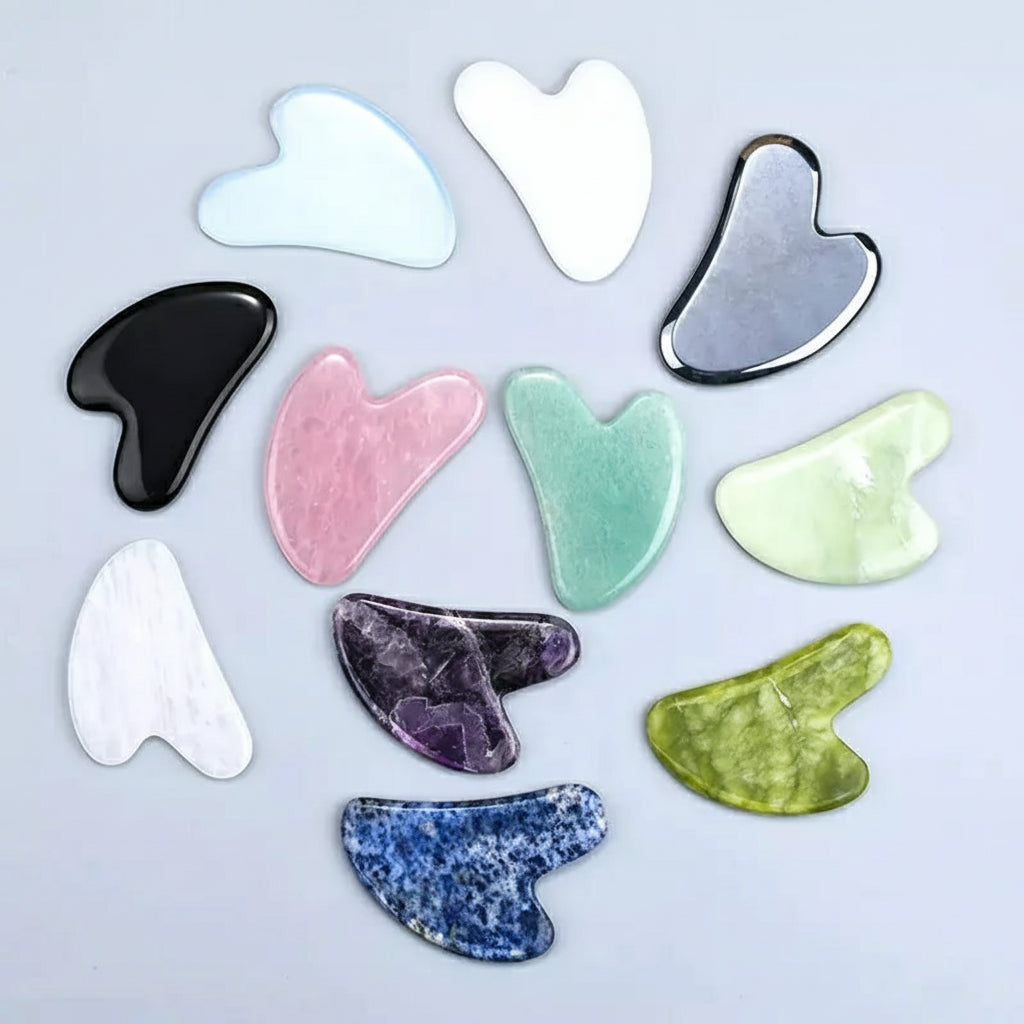 Collection of variously colored gua sha tools on a light gray background