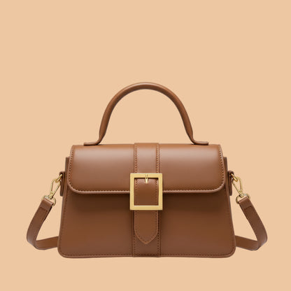 Brown handbag held by a person with a blurred background