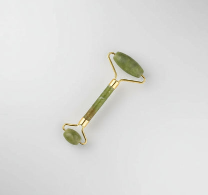 Jade facial roller with gold accents on a white background