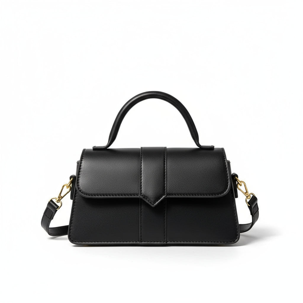 Black handbag with gold accents held by a hand on a light background