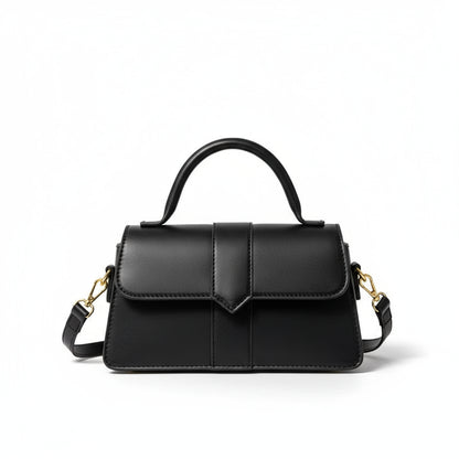 Black handbag with gold accents held by a hand on a light background