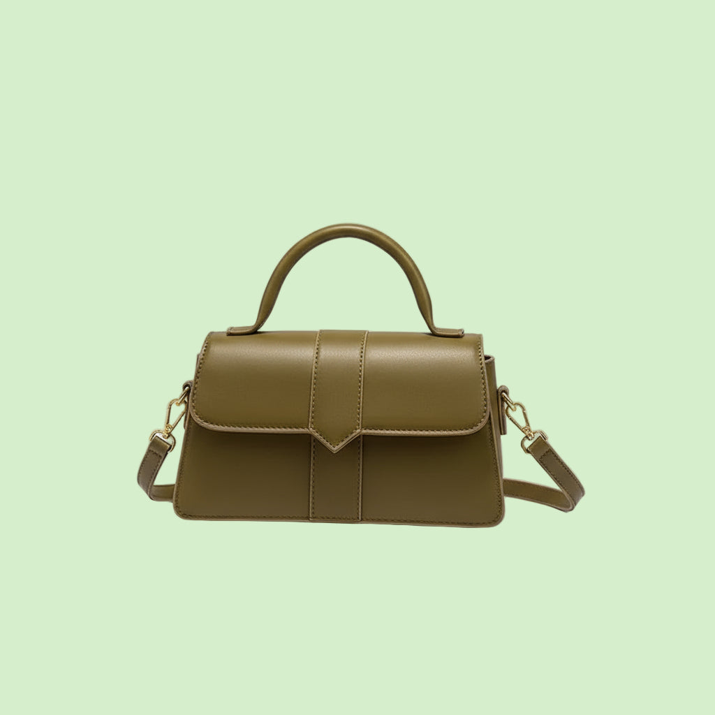 Green handbag held by a hand with red nail polish against a neutral background